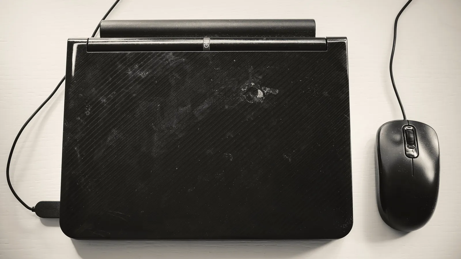 Closed black laptop and mouse on a white table