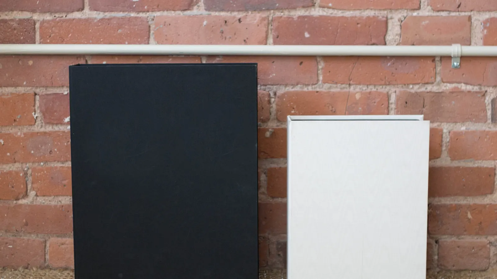 Black and white portfolio folders against a brick wall