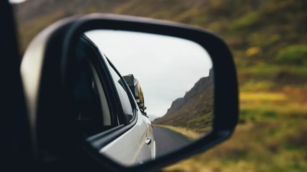 Car side mirror reflecting the road behind